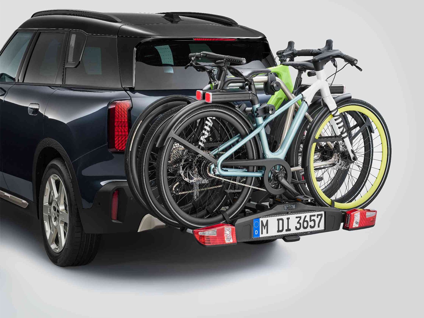 MINI Aceman in Nanuq White equipped with MINI rear bike rack Pro 3.0, carrying two mountain bikes and a child’s bike.